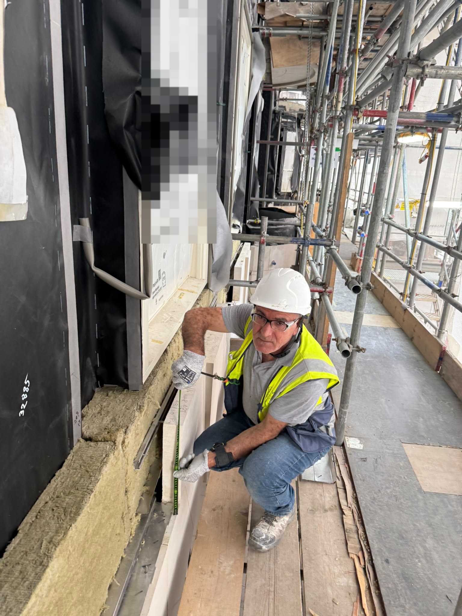 Stonemason measuring limestone cladding on site