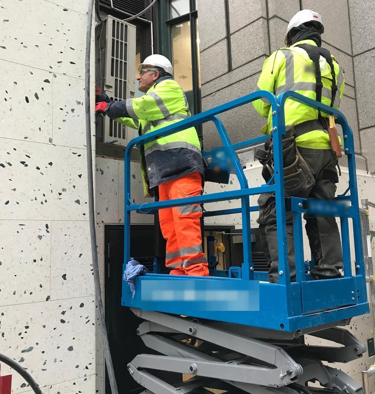 Stonemasons on a scissor lift working on terrazzo wall cladding